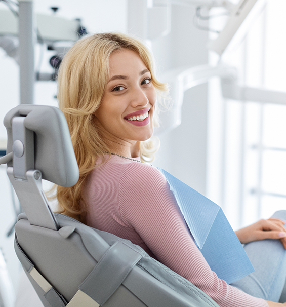 Blonde woman in the dental chair smiling over her shoulder
