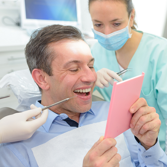Dental patient admiring his new smile in a mirror