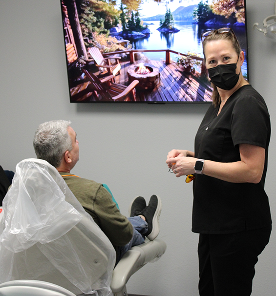 Dental team member talking to a patient in the treatment chair