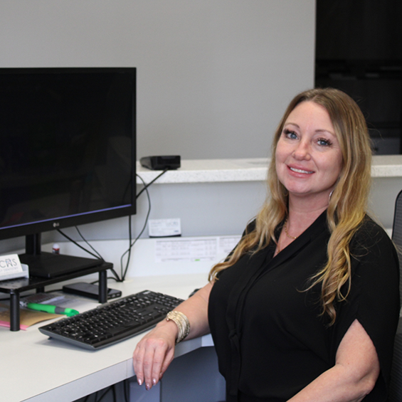 Smiling dental team member sitting at her desk with a computer