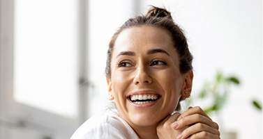 Woman in a white collared blouse smiling after dental services in Lucas