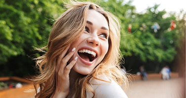 Young blonde woman grinning outdoors