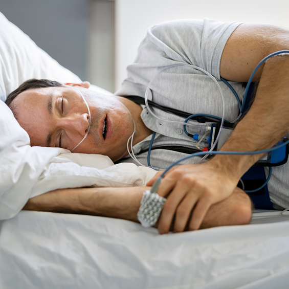 Sleeping man with attached electrodes and a pulse oximeter