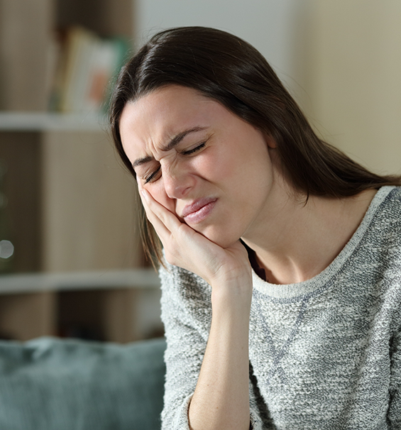 Woman holding the side of her jaw in pain before TMJ treatment in Lucas